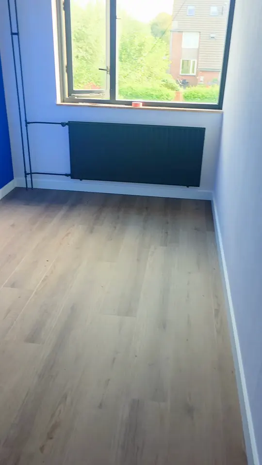 Laminaatvloer in een slaapkamer met blauwe wand