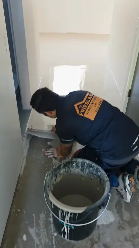 Vakman werkt de egaline af langs de wand